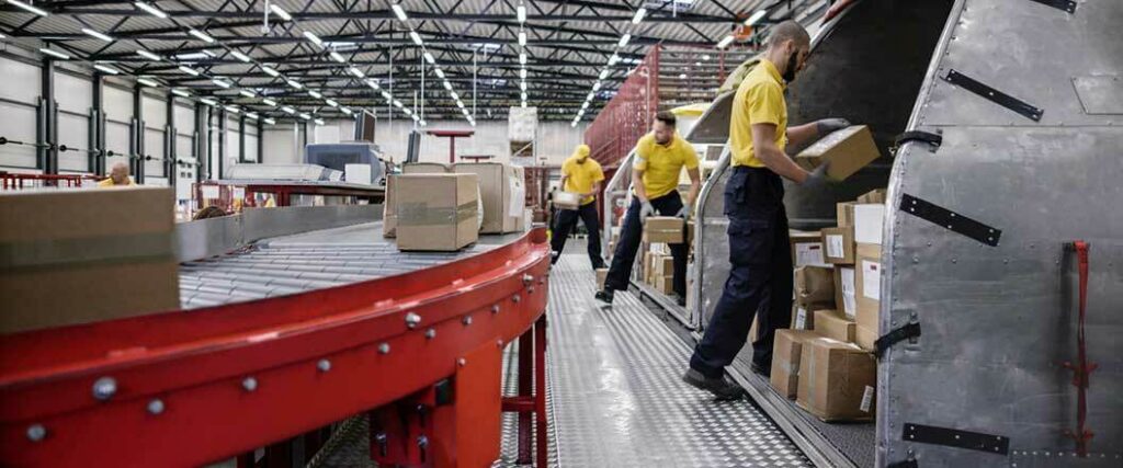 Warehouse employees sorting packages on a conveyor belt. 