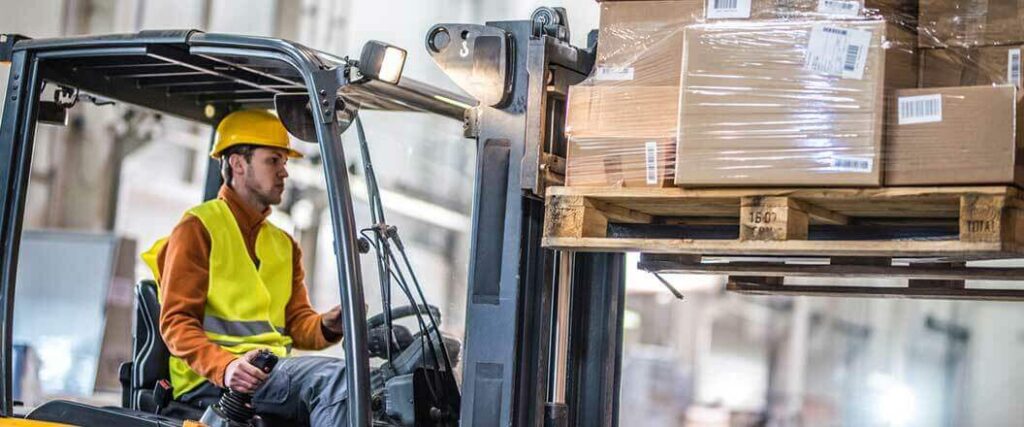 A warehouse worker using a palletized load with a forklift